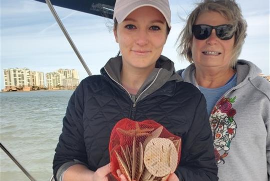 Two women posing for a photo and one holding shells found on the Family Fun Boating, Shelling, and Fishing Trip in Goodland Florida USA.