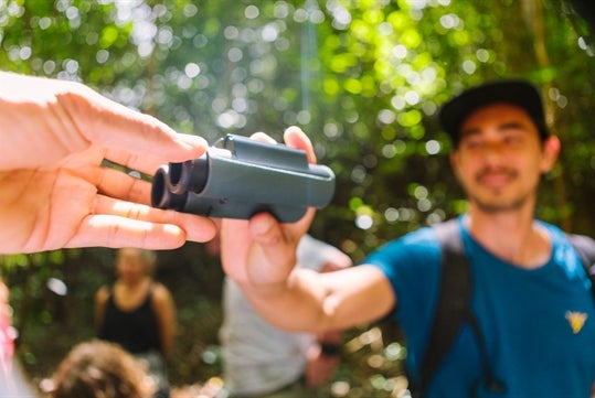 A tour guest getting handed binoculars on the Hakalau Birdwatching Tour in Kona Hawaii, USA.