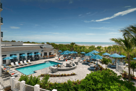 View of the outdoor pool with sun loungers at Hilton Garden Inn Cocoa Beach-Oceanfront, FL.