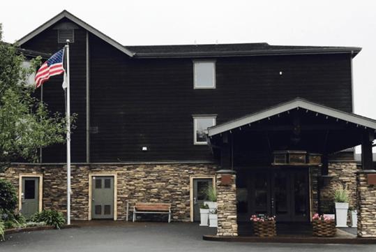 The dark wooden and stone exterior of the Holiday Inn Express Fort Bragg  on a foggy day.