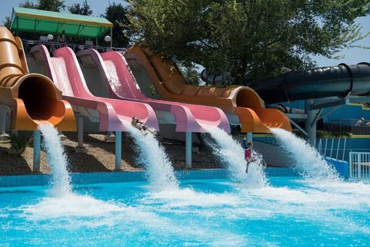 The end of Shotgun Falls water slide, featuring vibrant orange and pink colors, with riders splashing into the pool below.