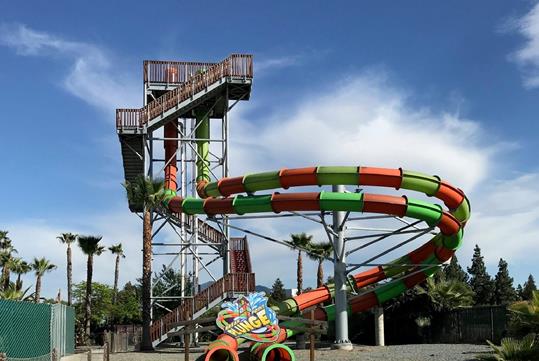 The Break Point Plunge, a large green and orange water slide with a twisting design.