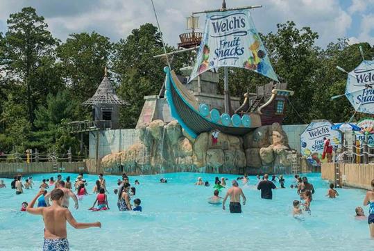 The Blue Lagoon featuring a wave pool filled with visitors and a Welches Fruit Snack themed pirate ship at the back.