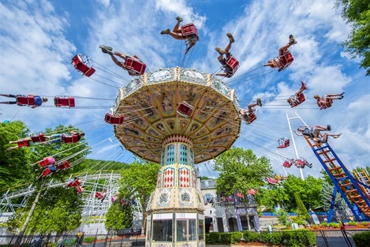 Park-goers are enjoying the carousel designed with vibrant colors as it spins around on a pleasant cloudy day at Idlewood.