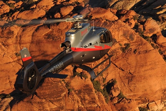 Maverick helicopter flying through the Red Rock Canyon which offers golden overlooking views of the rock formations.