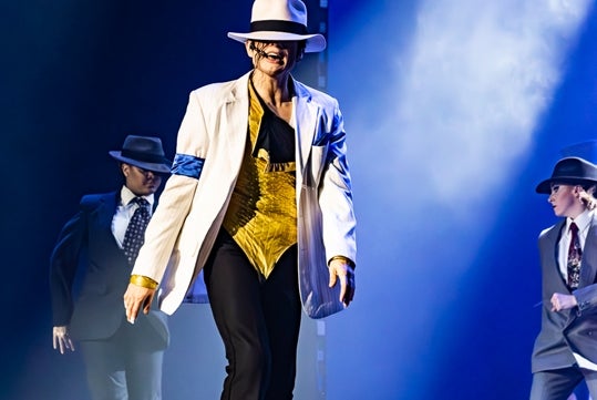 Michael Knight performs on stage as MJ wearing a yellow leotards and a white trouser together with his MJ Illusion team at Reza Live Theatre in Branson, Missouri.