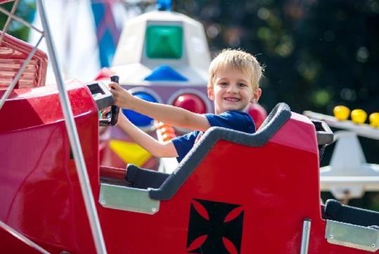 A young boy smiling while riding Airplanes and smiling at Michigan's Adventure in Grand Rapids, Michigan.