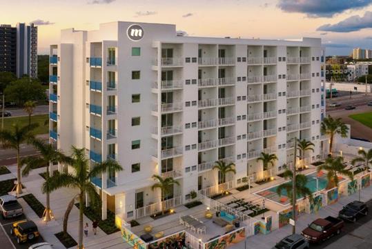 Aerial view of the Mint House hotel in downtown St. Petersburg with clouds and the sun setting behind it.