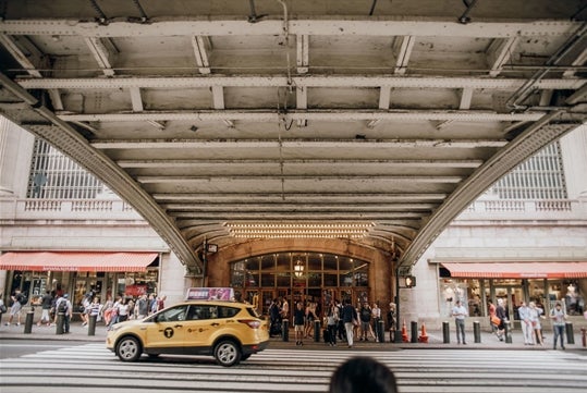 The underpass of a building with a crowd of people walking the sidewalk on the Must-See Manhattan Tour with SUMMIT One Vanderbilt Ticket in New York City, New York, USA.