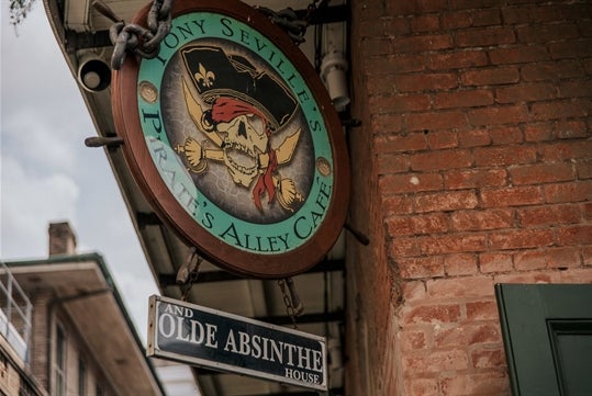 A sign for Pirate Alley Café with a pirate skull and sword graphic on the New Orleans: Secrets & Highlights of the French Quarter Tour in New Orleans, Louisiana, USA.
