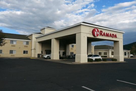 The front coverd entrance of the Ramada by Wyndham Williams/Grand Canyon Area with cars parked under it on a sunny day.