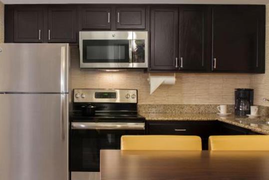 A kitchen with black and silver appliances, dark cabinets, granite countertops at Residence Inn Tampa Downtown in Tampa, Florida, USA.