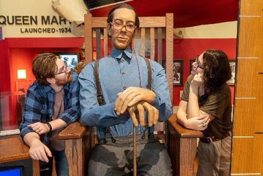 Couple posed with Wadlow, a large man with glasses and a blue shirt sitting in a giant chair, at San Antonio Ripleys Believe It or Not!.