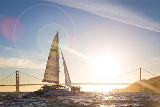 The Adventure Cat catamaran at sunset with the Golden Gate Bridge in the background
