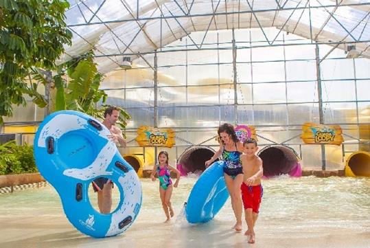 A family carrying blue tubes and laughing at Schlitterbahn New Braunfels in San Antonio, Texas.