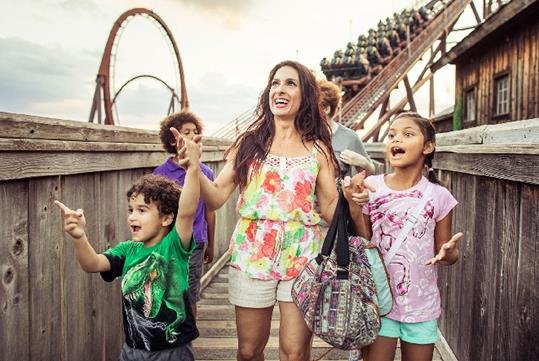 A family with small children walking with the Wild Fire roller coaster behind them at Silver Dollar City in Branson, Missouri.