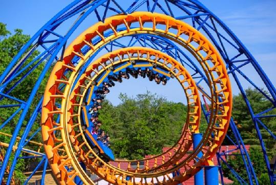 A group of park-goers going through the spiral of the Steamin' Demon on a sunny day at Six Flags Great Escape.