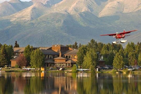 View of Lakefront Anchorage on the shore of Lake Spenard, a sea plane, and the majestic Chugach Mountains behind.