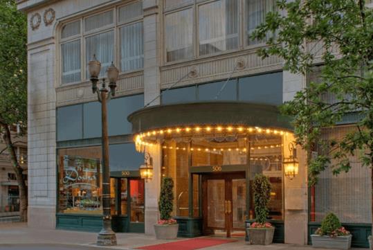 The front entrance to the The Royal Sonesta Portland Downtown with warm lights hanging over it at dusk.