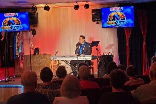 Greg Stout performing on the stage with his Keyboard instrument in front of his audience