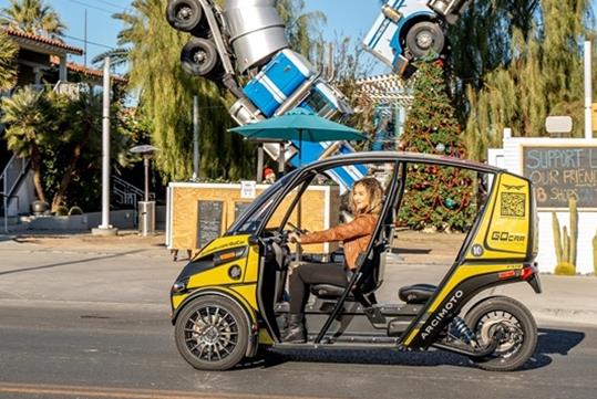 A woman driving a doorless GoCar past a train sculpture on a sunny day in Las Vegas, Nevada.