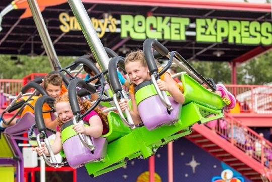 Young girls riding Snoopy's Rocket Express and smiling on a sunny day at Valleyfair in Bloomington, Minnesota.