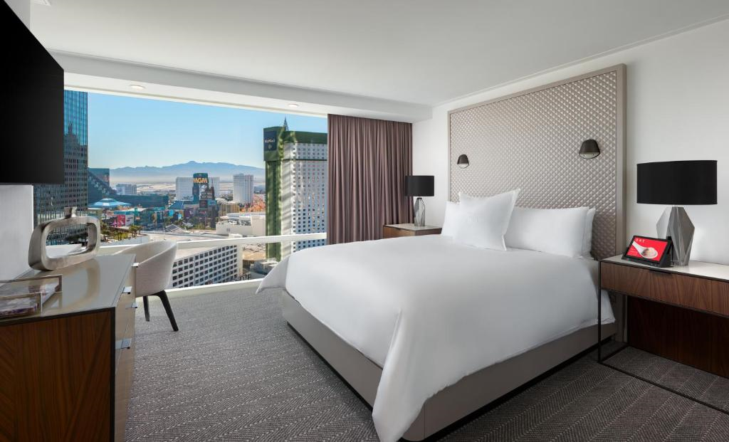 Guest room with a king bed, and large windows with view of the city.