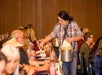 A woman in a plaid shirt serving food to a row of guests at the A Christmas Story Dinner Show.