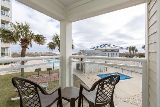 Furnished patio with a view of the beach and the pool area.