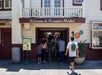 People walking into a building with a "Welcome to Farmers Market" sign above the entrance.