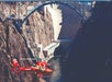 A red helicopter flies in a canyon below an arched bridge and near a large concrete dam.