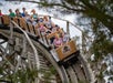 A roller coaster car full of people screaming while going around a corner on the wooden coaster The Outlaw at Adventureland.