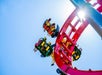 View looking up at park guests strapped into their seats on the red Dragon Slayer coaster with some guest upside down on a sunny day at Adventureland.