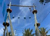 Person navigating a high ropes course outdoors, with a clear blue sky and trees in the background.