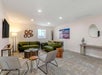 A common area with two green couches, chairs, coffee table, art on the walls and a flat-screen TV at theAiden by Best Western.