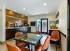 A breakfast area with table and chairs, cabinets on the left and right walls with a breakfast bar on top, and a glass door leading to a patio.
