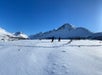 Tour guests hiking along a snow-covered trail in Chugach State Park with mountains in the background.