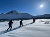 Group of hikers with trekking poles in hand trekking along a snow-covered trail in Chugach State Park.