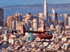 A red helicopter flying through the air with the city of San Francisco in the background at sun set on the Alcatraz and San Francisco Sites Helicopter Tour.