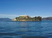 A view of Alcatraz Island with its historic buildings surrounded by blue waters under a clear sky.