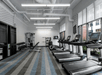 A fitness center with a row of cardio equipment in front of the windows and a weights area behind them at the Aloft Columbus Easton.