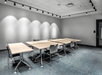 A meeting room with blue carpet, gray walls, six tables pushed together and a few chairs at the tables at the Aloft Columbus Easton.