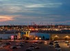 Amusement park with lit rides in the distance, seen from a parking lot at dusk.