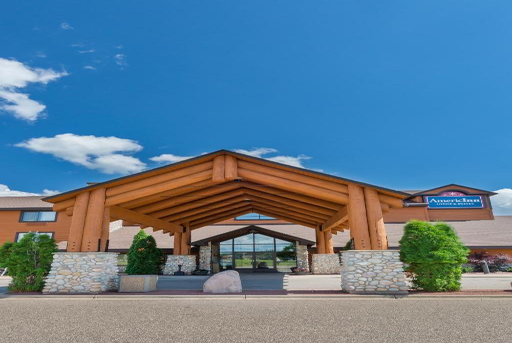 Entrance of a lodge with wooden beams, stone pillars, and a clear blue sky in the background.
