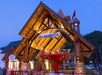 The image shows the Anakeesta entrance building at dusk, featuring exposed wooden beams, stone pillars, and a covered chairlift loading area.