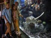 A group of children and adults observe a sea turtle swimming in a large aquarium exhibit with coral and rocks.