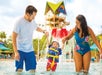 A mother and father holding their child's hand and swinging them in the water at Aquatica in Orlando, Florida.