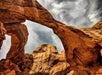 A stunning view looking up at the famous "Double Arch" with a cloudy sky overhead at  Arches National Park in Utah