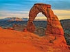 An impressive arch formation in the rock with the sunset and mountains in the background on the Arches National Park Sunset Discovery Tour Moab Utah.