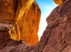Two people looking at the sun setting through one of the enormous arches on the Arches National Park Sunset Discovery Tour Moab Utah.